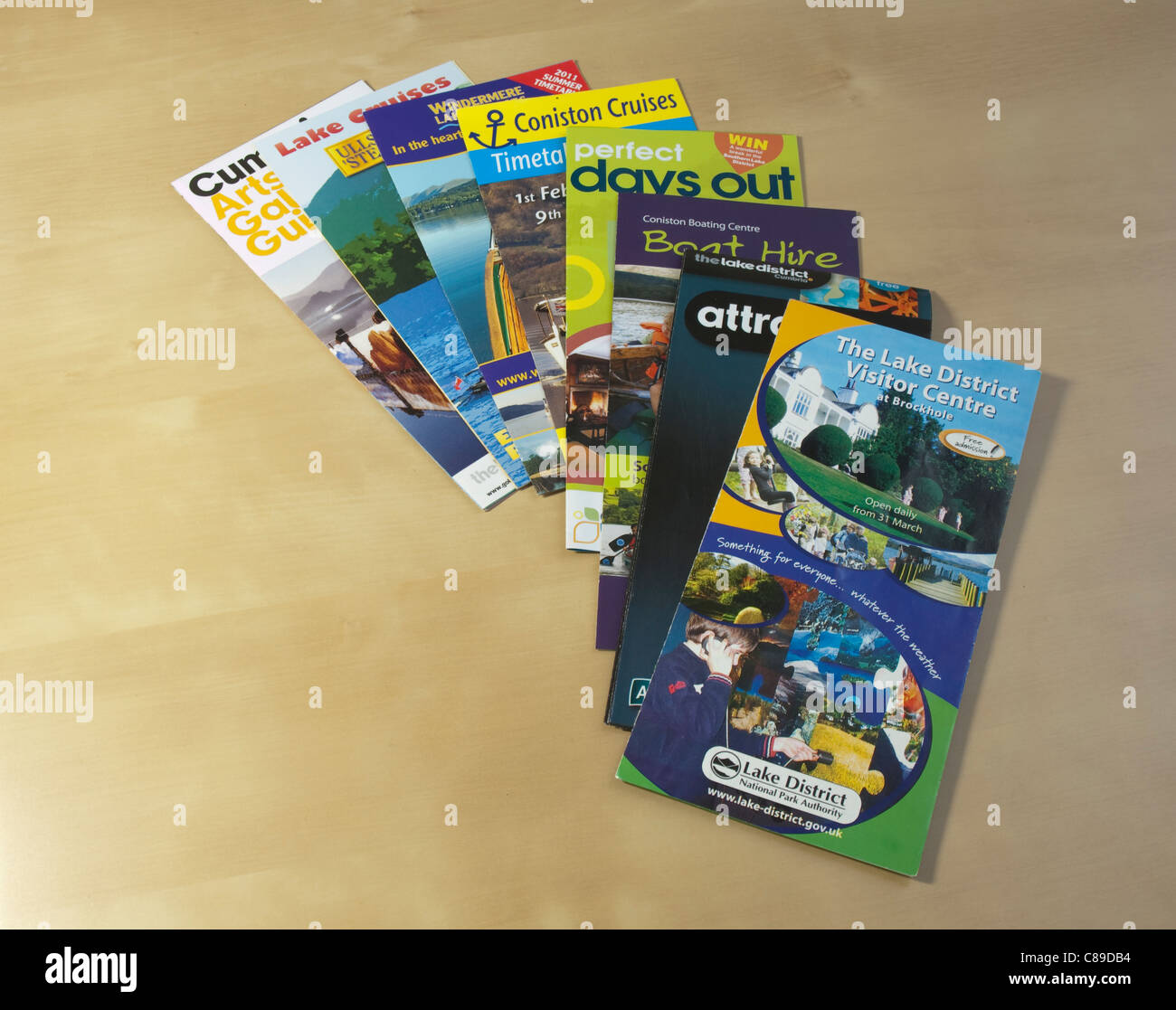 Lake District visitor attractions leaflets on a light pine wood finish table Stock Photo