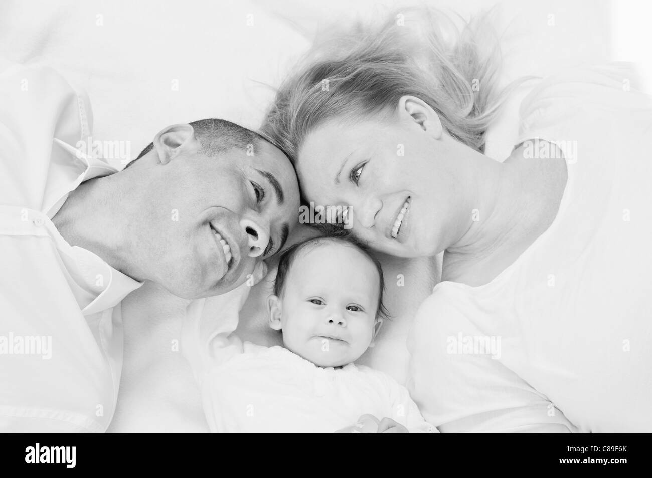 Germany, Bavaria, Father, mother and daughter lying on blanket, smiling Stock Photo