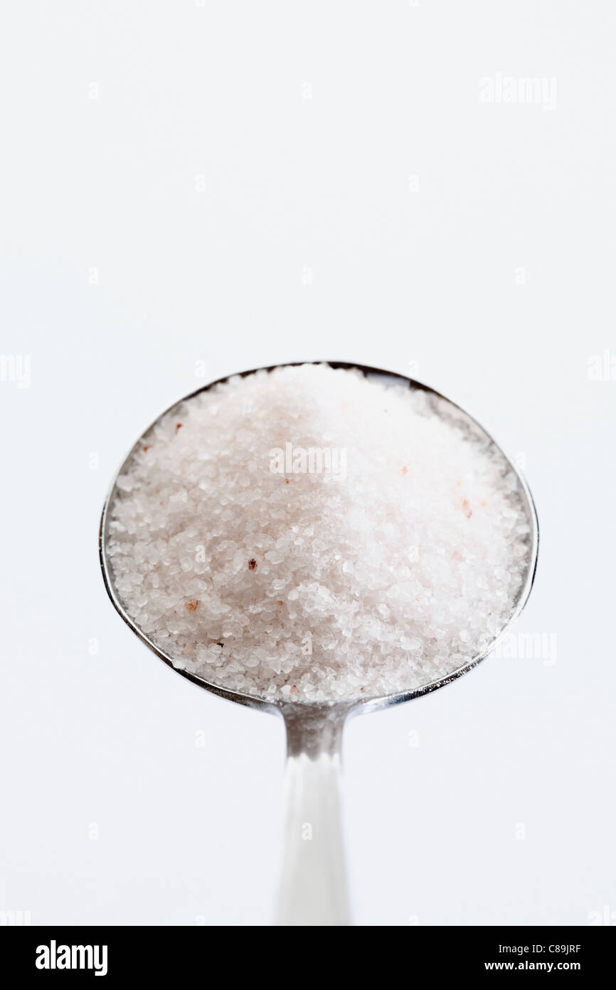 Spoon full of Himalayan Salt against white background, close up Stock Photo