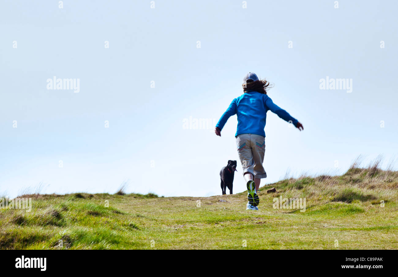 Child running up hill with dog Stock Photo