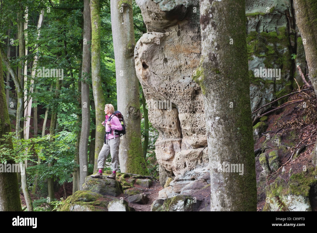 Germany Woman hiker standing near bunter rock formations at beech tree forest Stock Photo