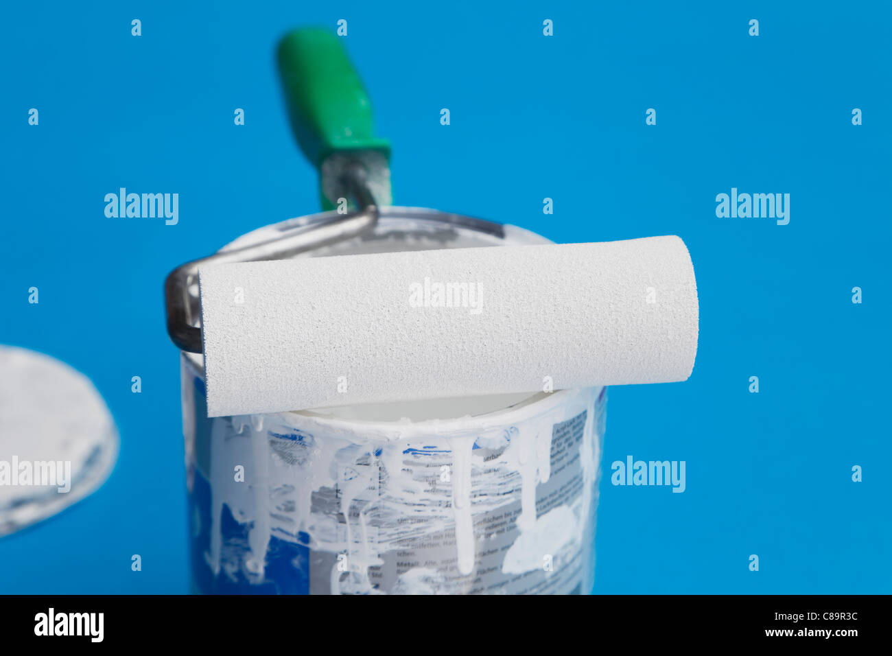 Used paint roller on white varnish of paint tin on blue background ...