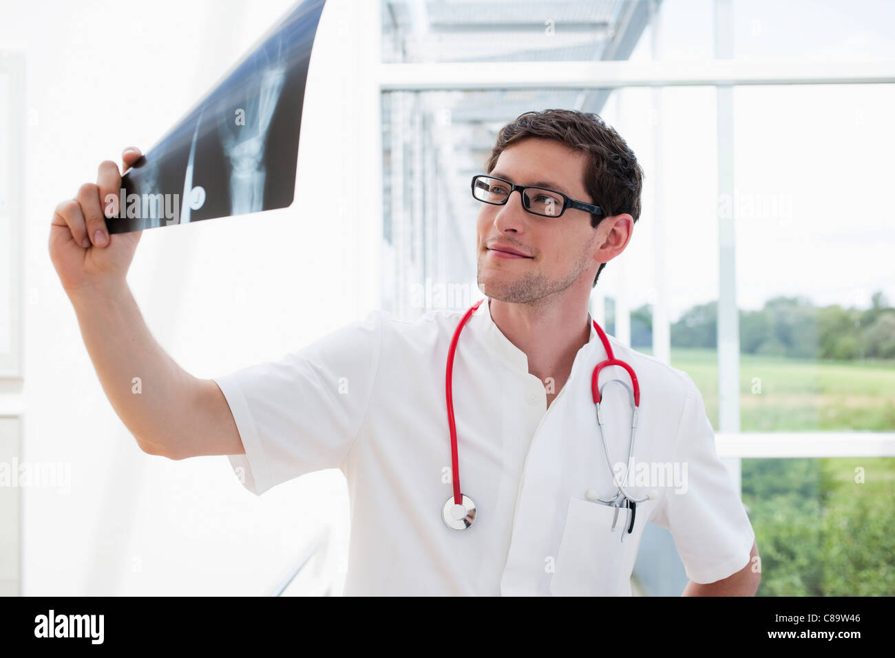 Germany, Bavaria, Diessen am Ammersee, Young doctor examining x-ray, smiling Stock Photo