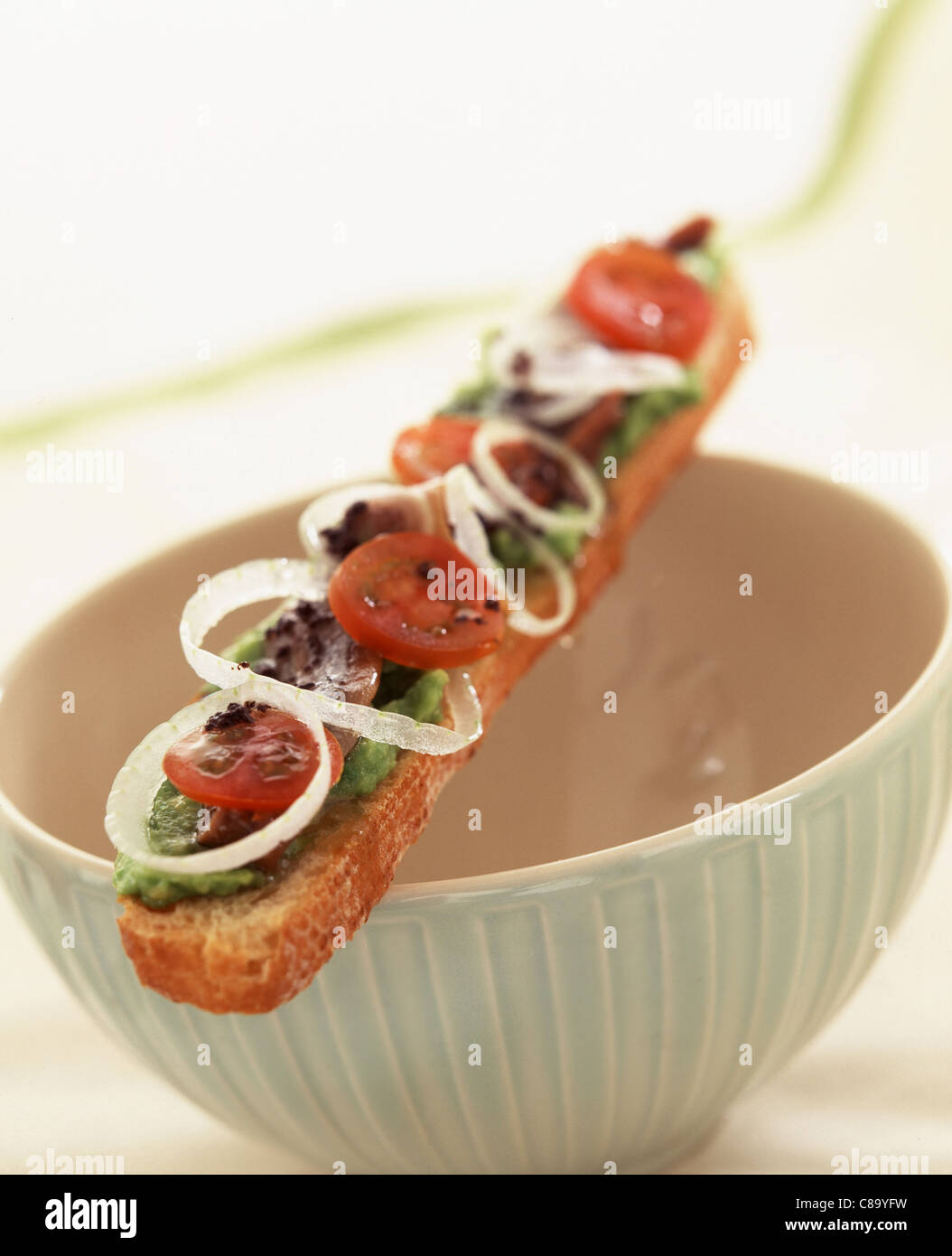 Long open sandwich with avocado, tomato and onion rings Stock Photo