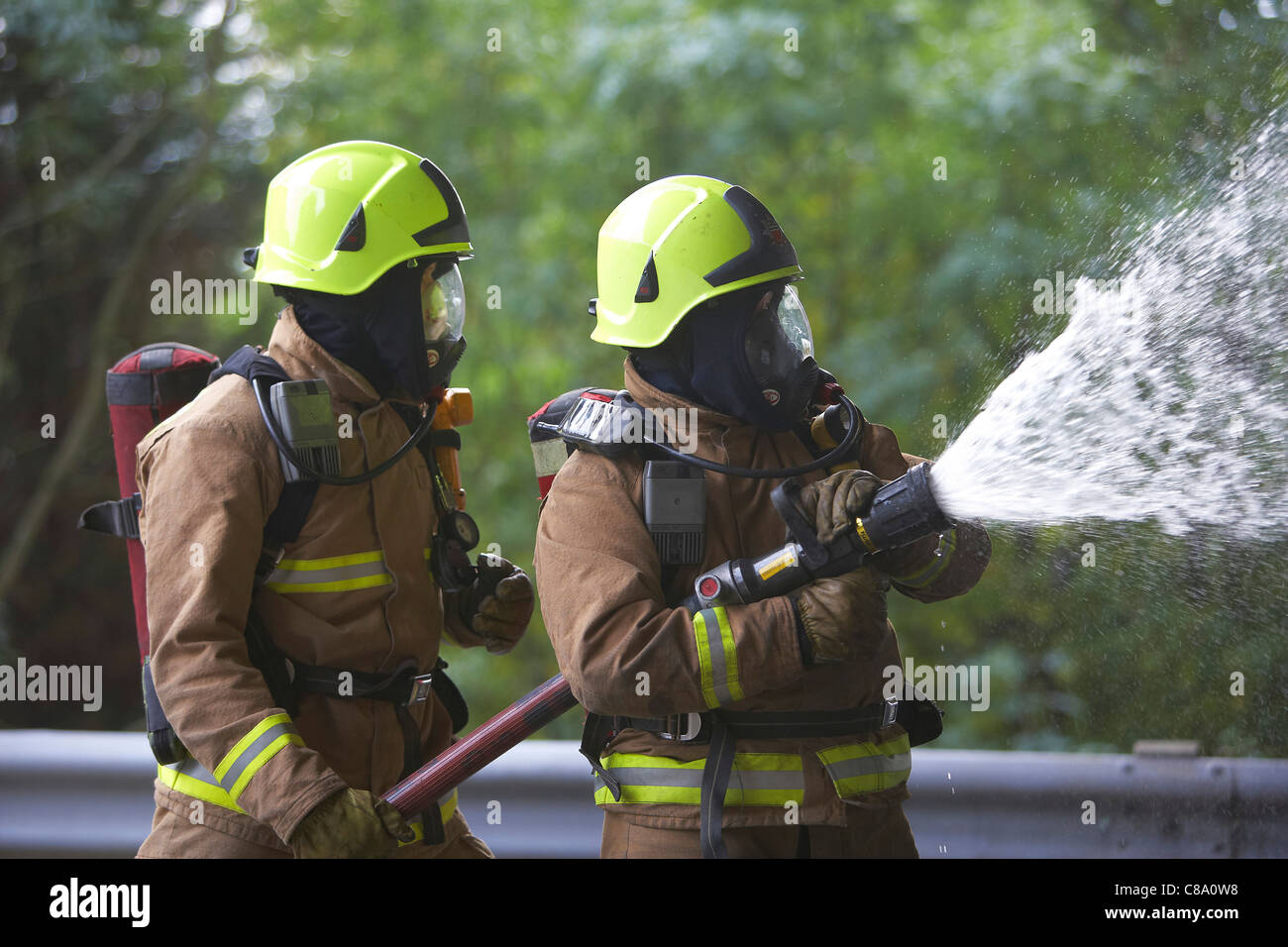 Firefighters with a hose wearing breathing apparatus, UK Stock Photo