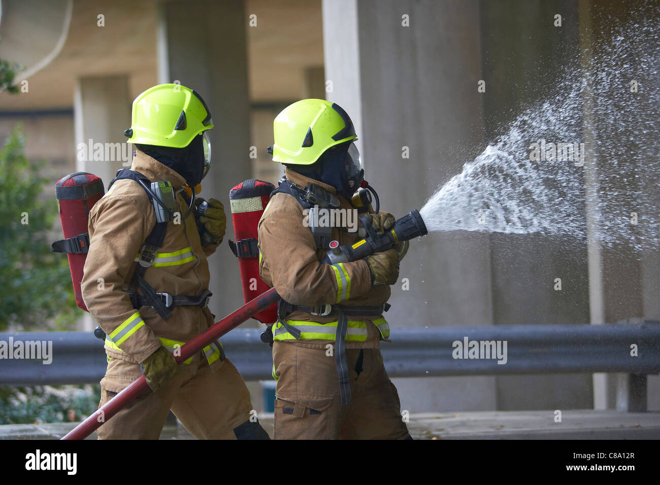 Firefighters with a hose wearing breathing apparatus, UK Stock Photo