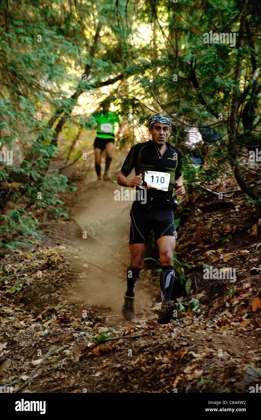Man running downhill in cross country trail race in forest Stock Photo