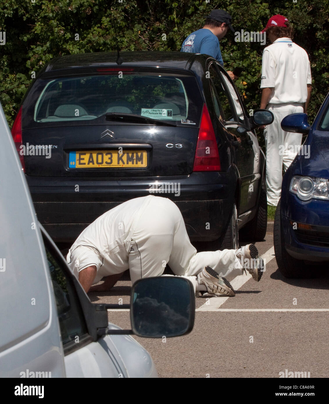 Searching for a lost ball in the car park at a village cricket match