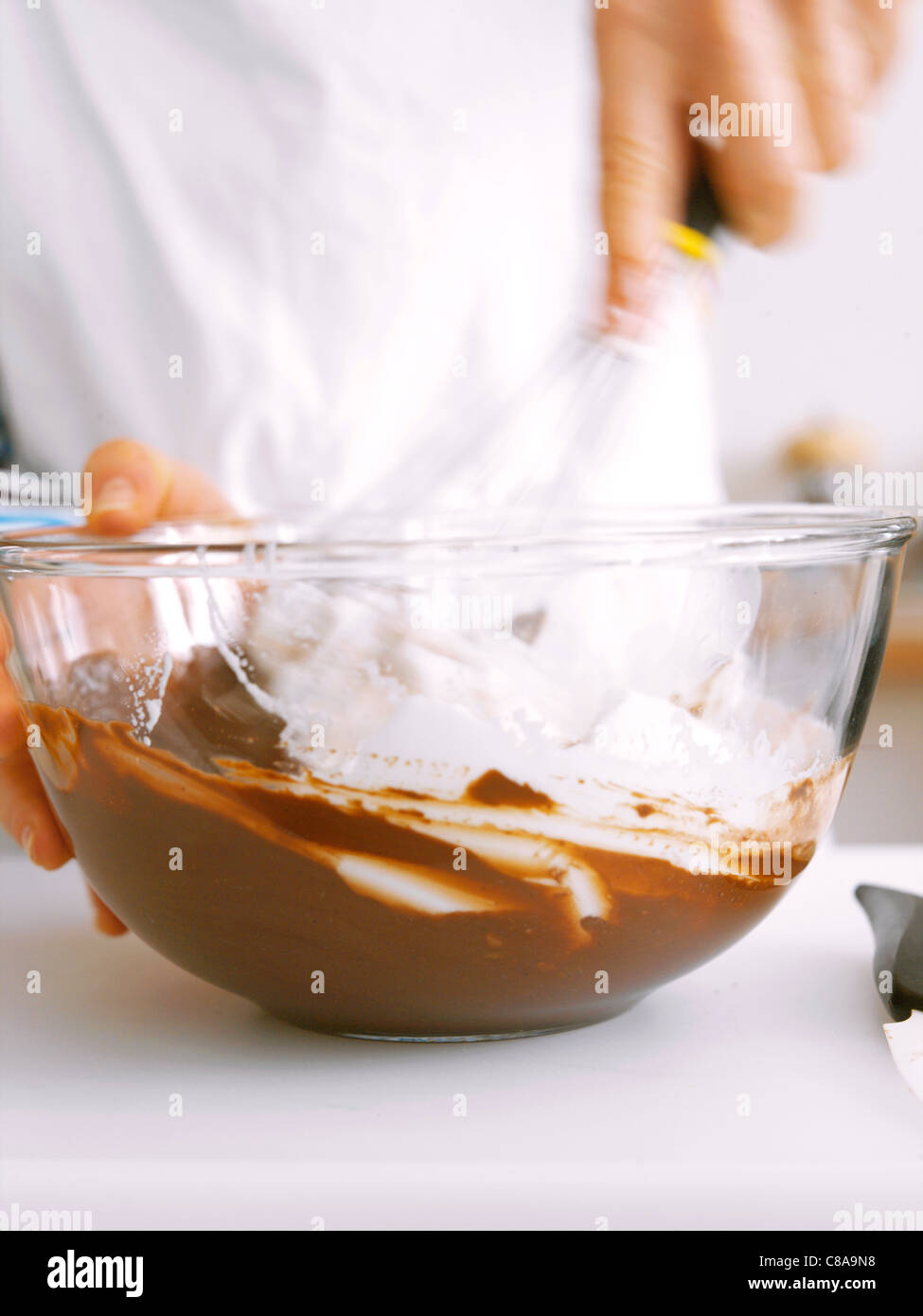 Adding the beaten egg whites to the chocolate mixture Stock Photo