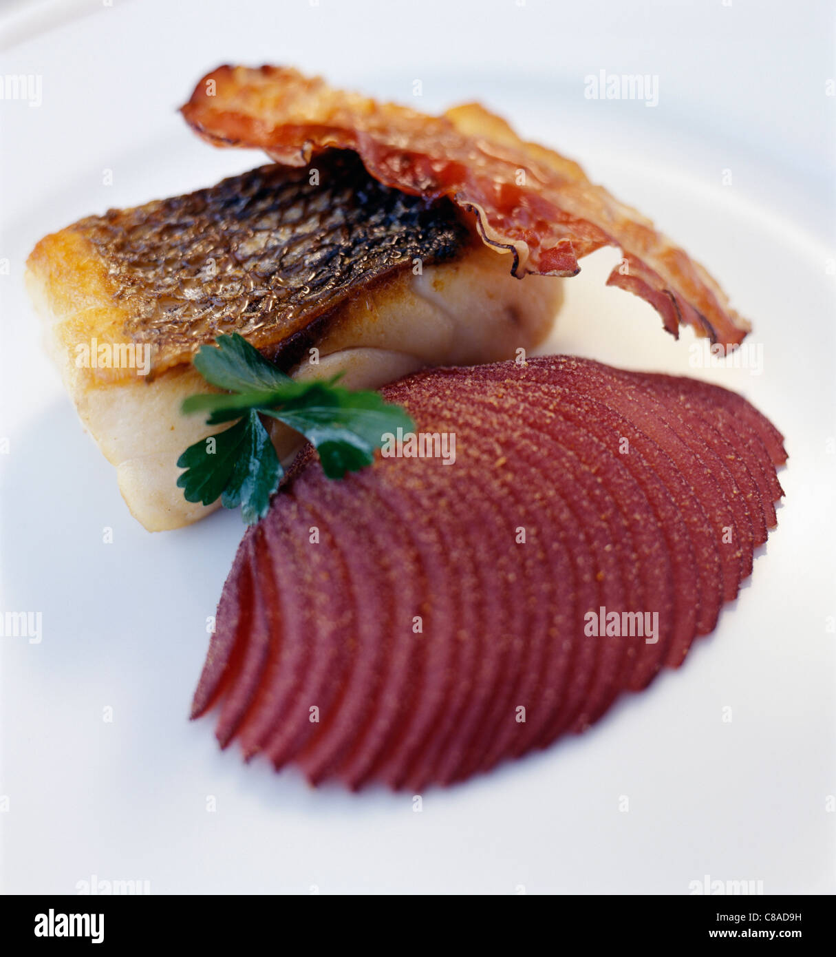 Piece of cod with crunchy bacon and finely sliced spicy beetroot Stock Photo