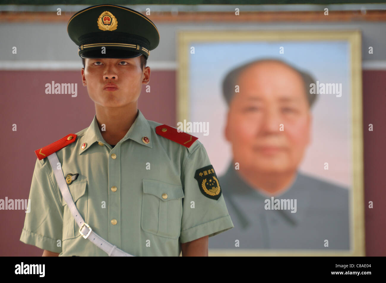 Chinese soldier standing in front of Mao's portrait in Beijing Stock Photo