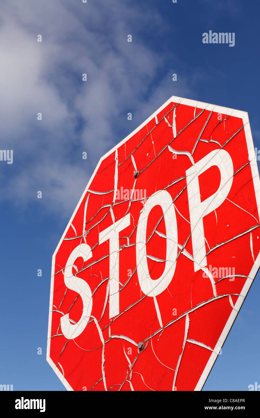 A cracked and worn stop sign against blue sky. Stock Photo