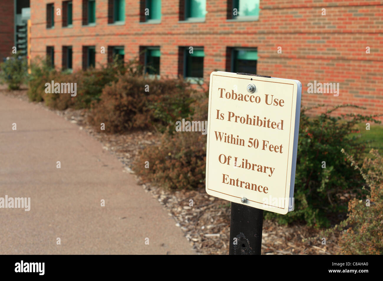 A sign reading 'Tobacco Use Is Prohibited Within 50 Feet Of Library Entrance.' Stock Photo