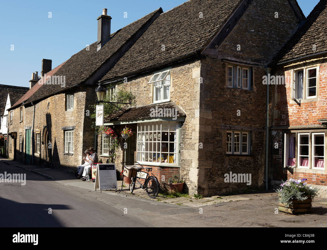 Two tourists eating ice creem outside the Tea Room, Lacock Village, Wiltshire, England UK Stock Photo