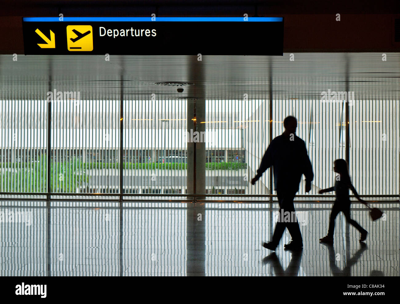 AIRPORT DEPARTURES FAMILY Father and young 4-6 years daughter in silhouette on contemporary concourse walk walking to airport terminal departures gate Stock Photo