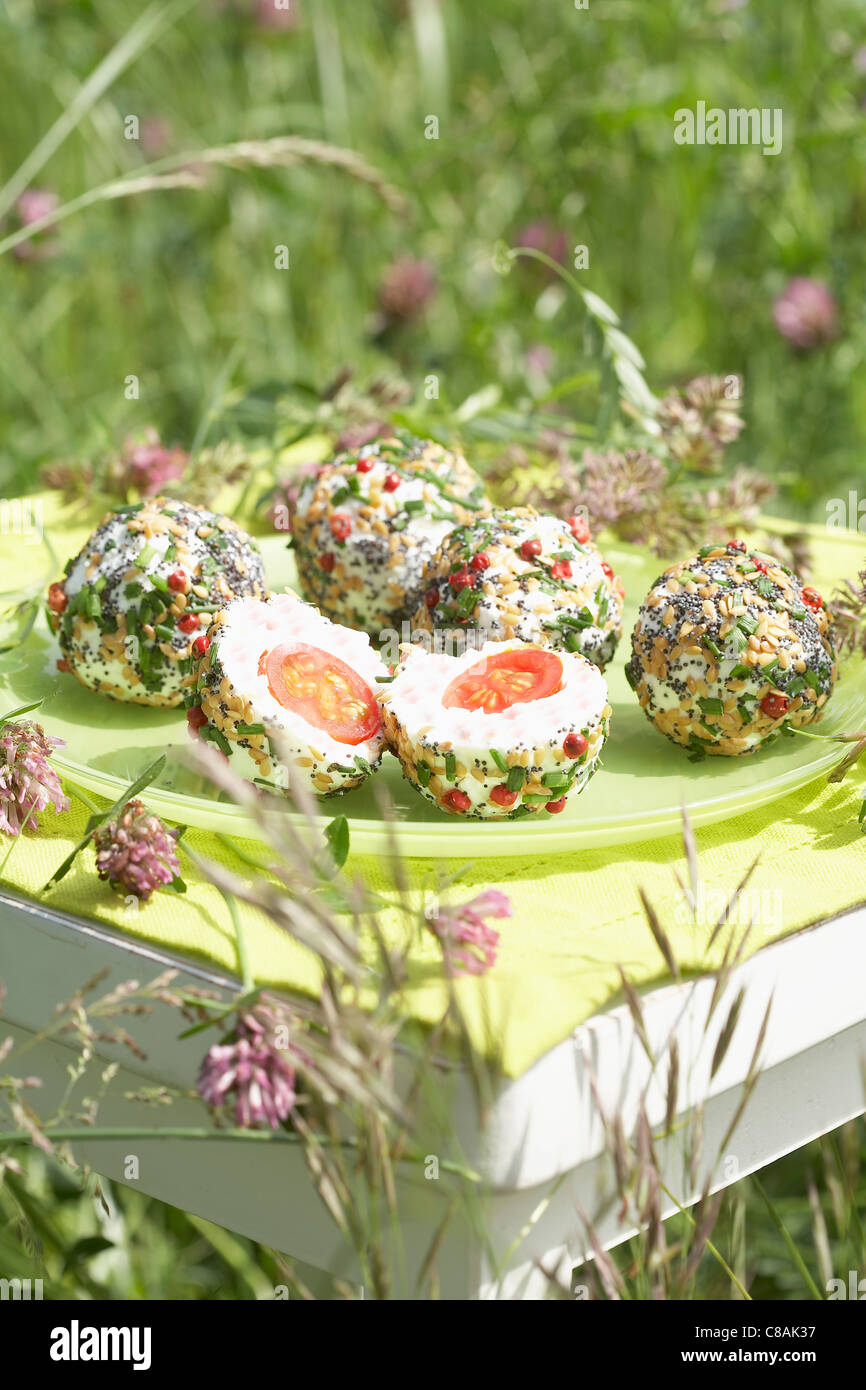 Cherry tomato and goat's cheese balls coated with poppyseeds,pine nuts and pink peppercorns Stock Photo