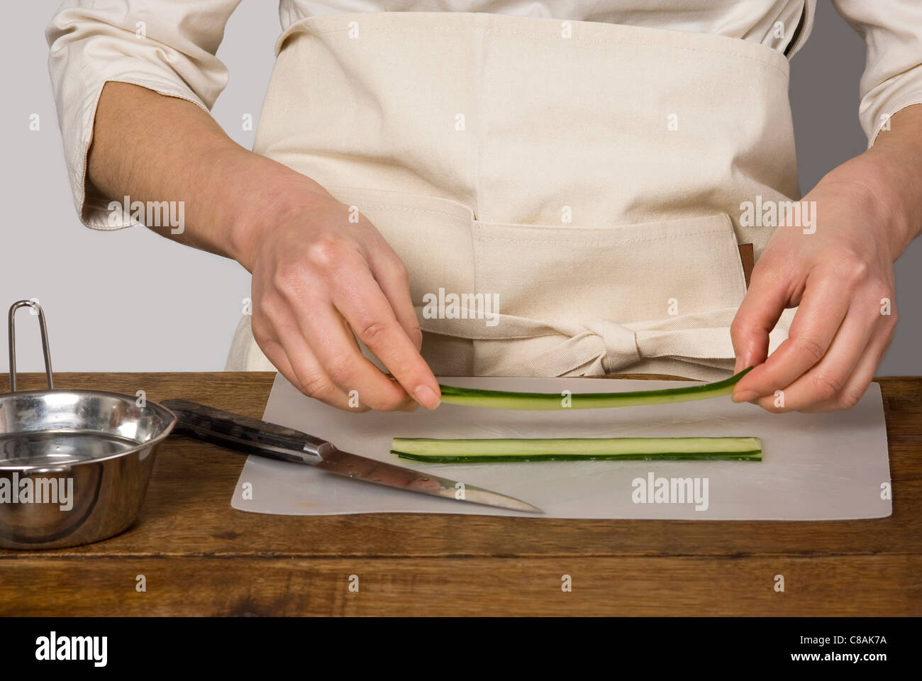 Cook preparing cucumber slices for the makis Stock Photo