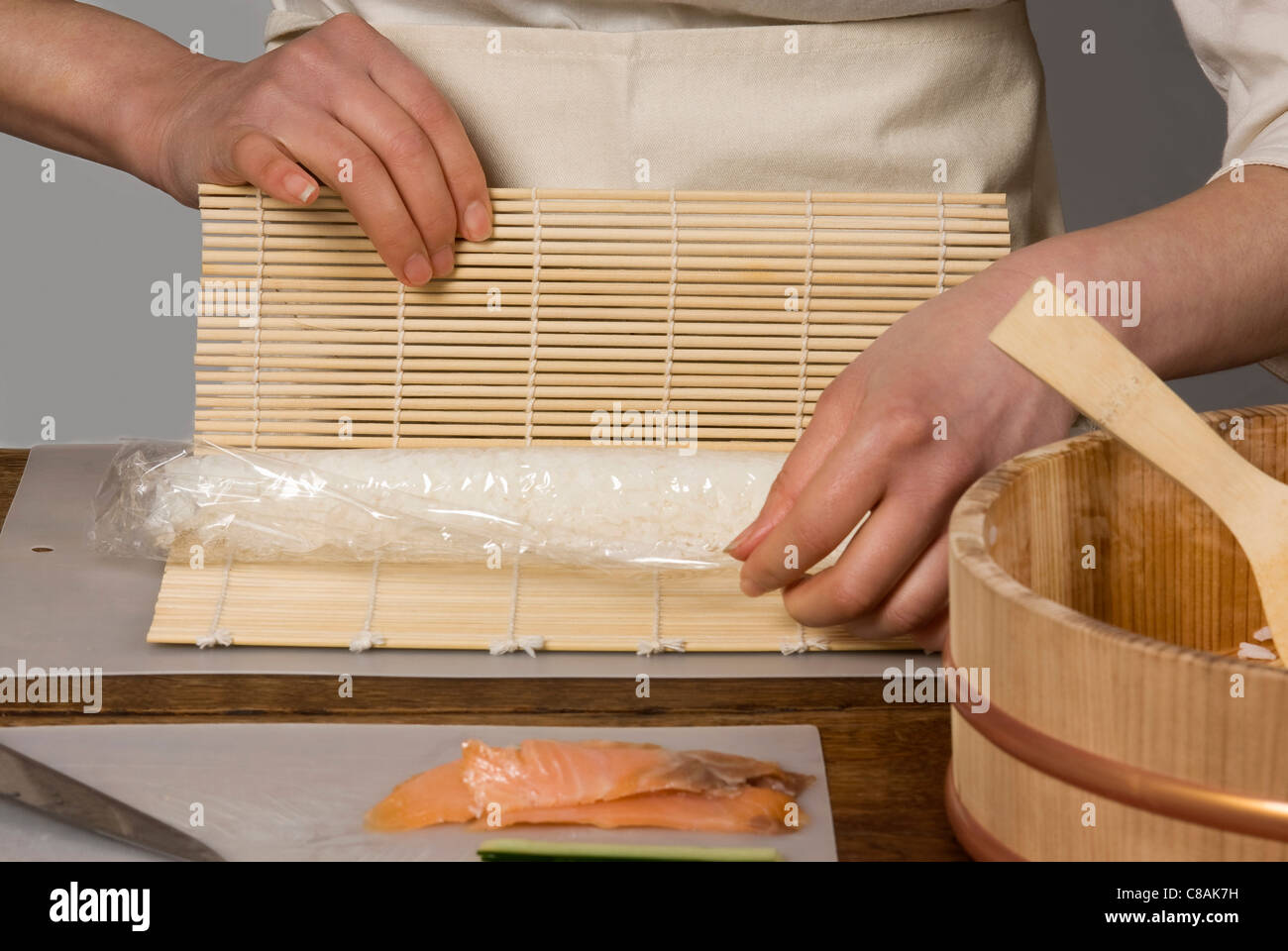 Cook rolling the rice in a mat for makis Stock Photo