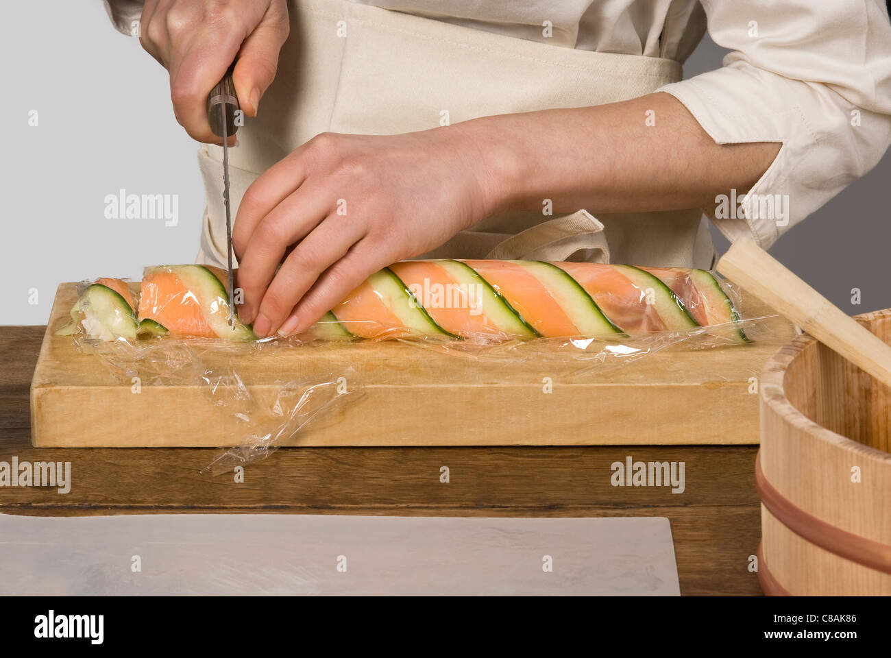 Cook slicing the salmon and cucumber makis Stock Photo