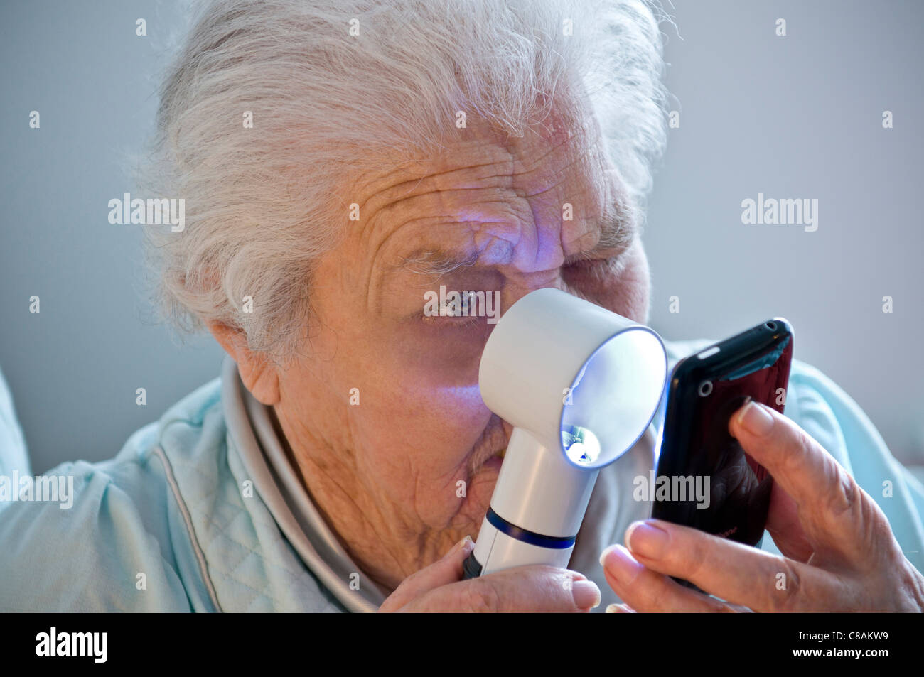 ELDERLY TECHNOLOGY MACULAR DEGENERATION Elderly lady with poor age related sight impairment learning to use her new technology Apple iPhone smartphone Stock Photo