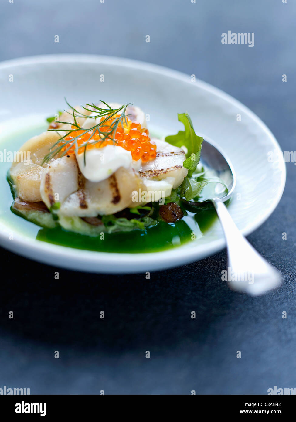 Green cabbage broth with scallops and salmon roe Stock Photo
