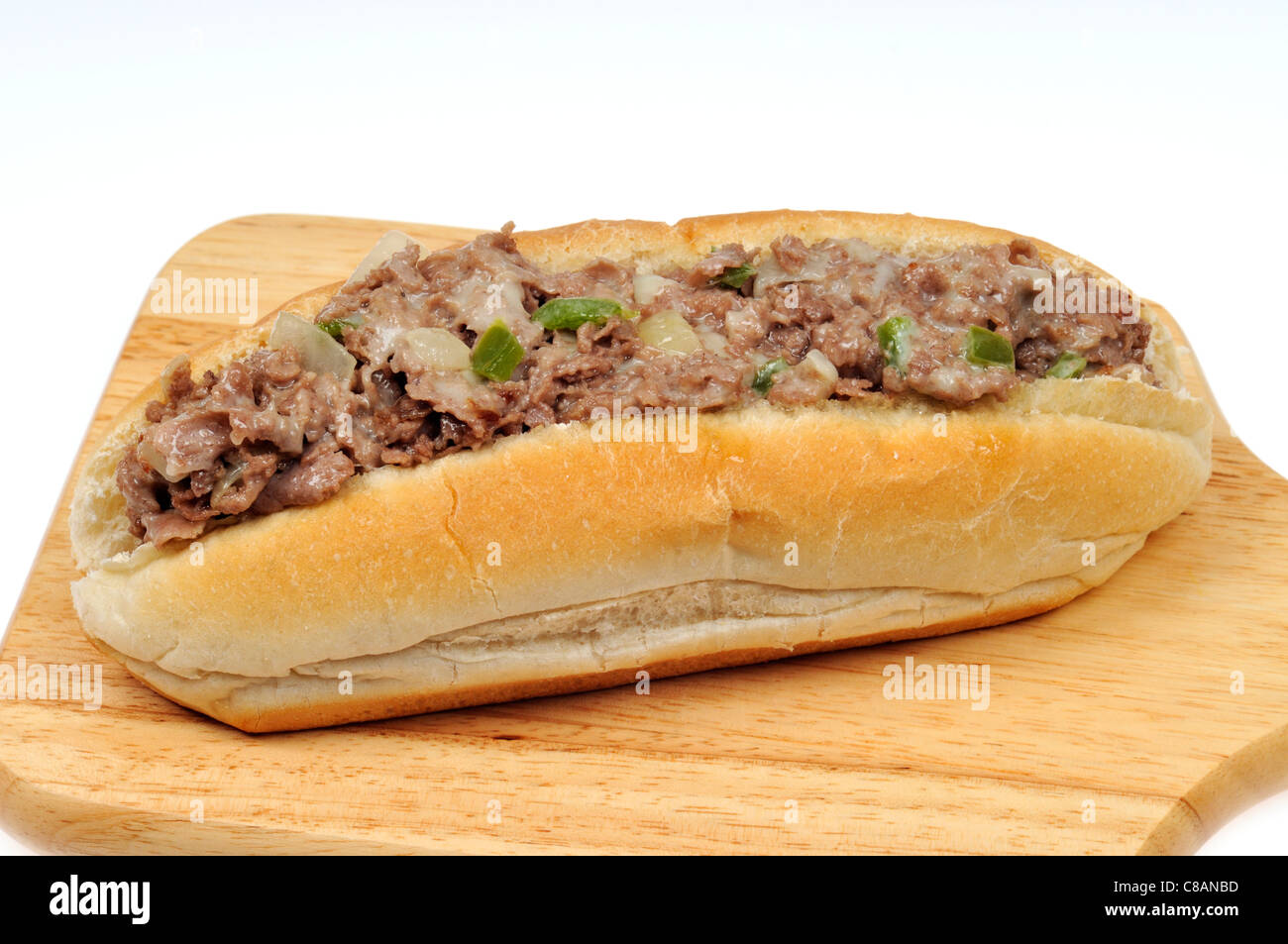 Closeup of a Philly cheesesteak on a wood cutting board with a white background. Stock Photo