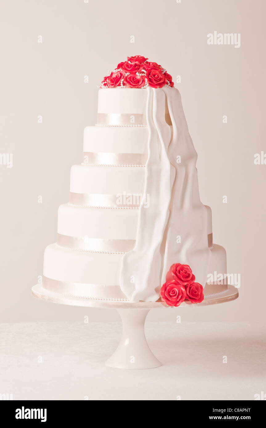 White wedding cake with red roses on white background Stock Photo