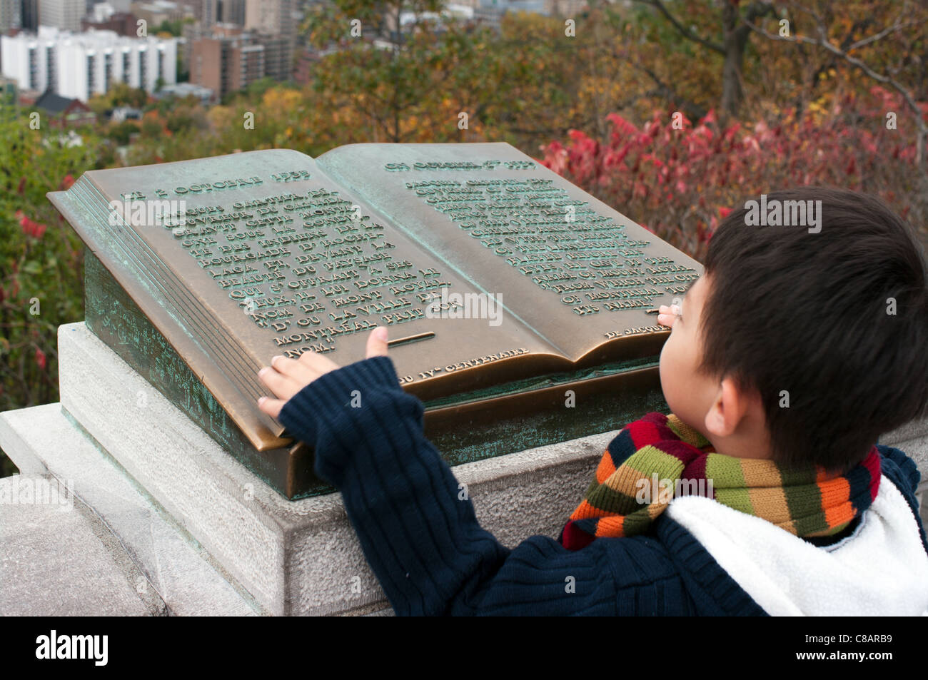Asian boy starring at the book on Mount Royal, Montreal, Quebec Stock Photo