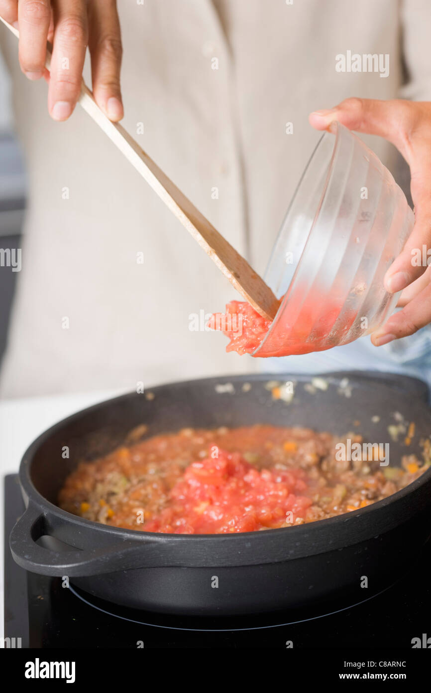 Adding the tomatoes to the preparation Stock Photo