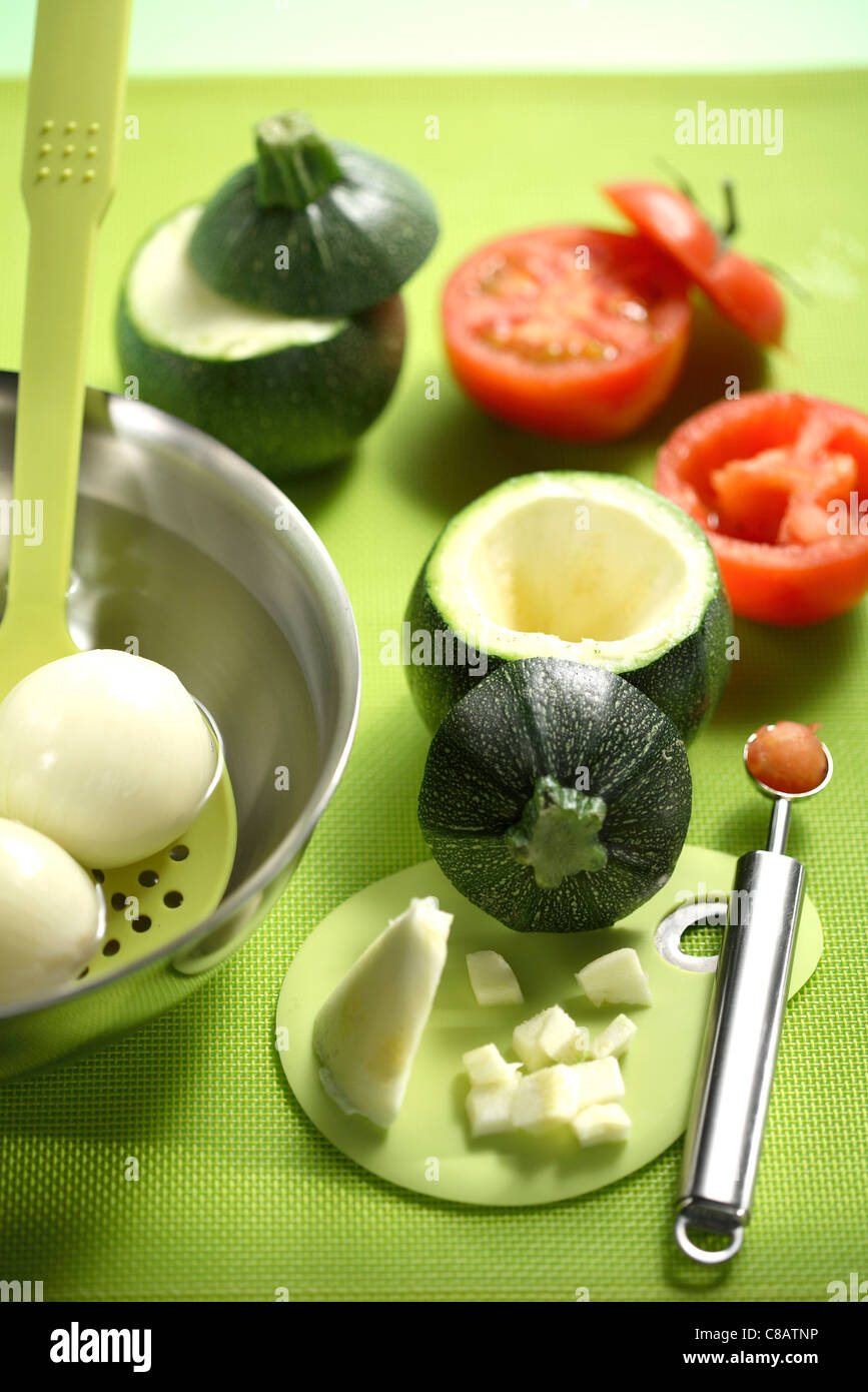 Scooping out the insides of the tomatoes and the round zucchinis Stock Photo