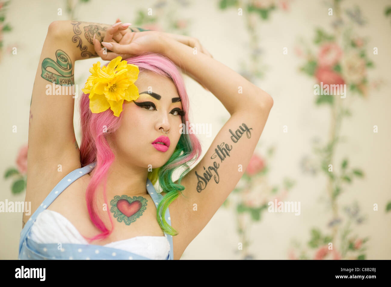 Close-up of young woman with flower in head and arms raised Stock Photo