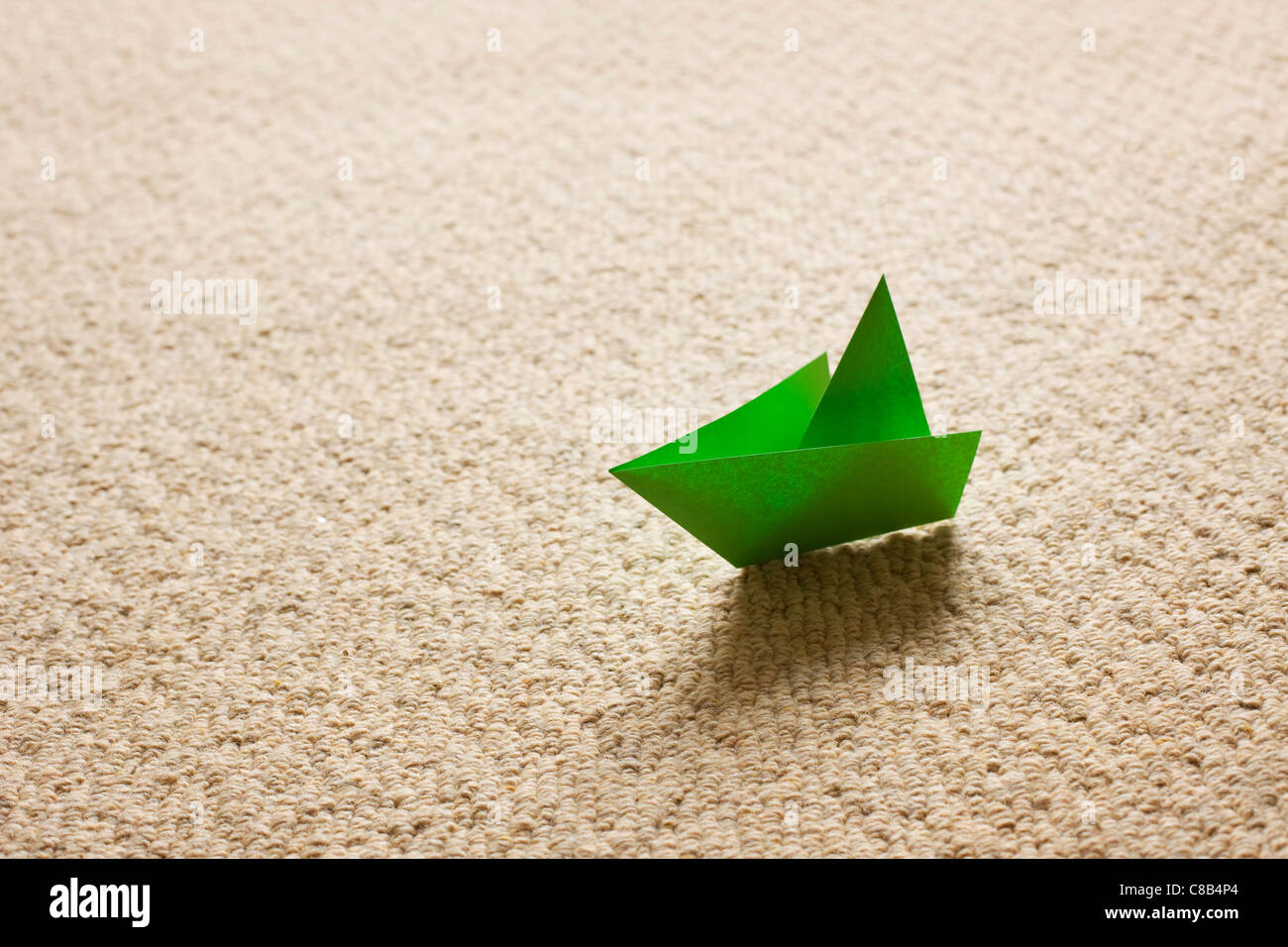 Green origami boat on carpet Stock Photo