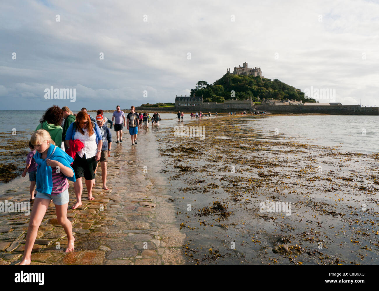 People walking on the causeway across to St Michaels Mount at low tide in Cornwall Britain Stock Photo