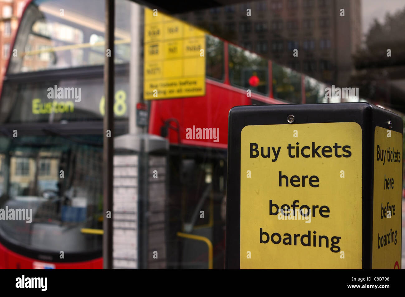 a sign showing Instructions where to buy bus tickets, with an out of focus bus waiting at the bus stop in the background Stock Photo