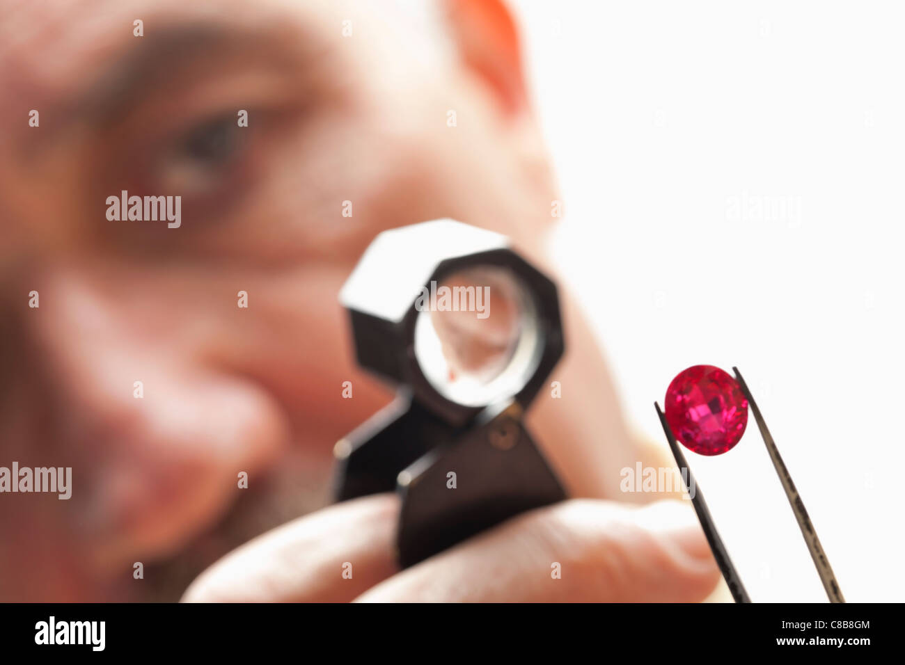 Close up of gemstone with jeweler looking through magnifying glass
