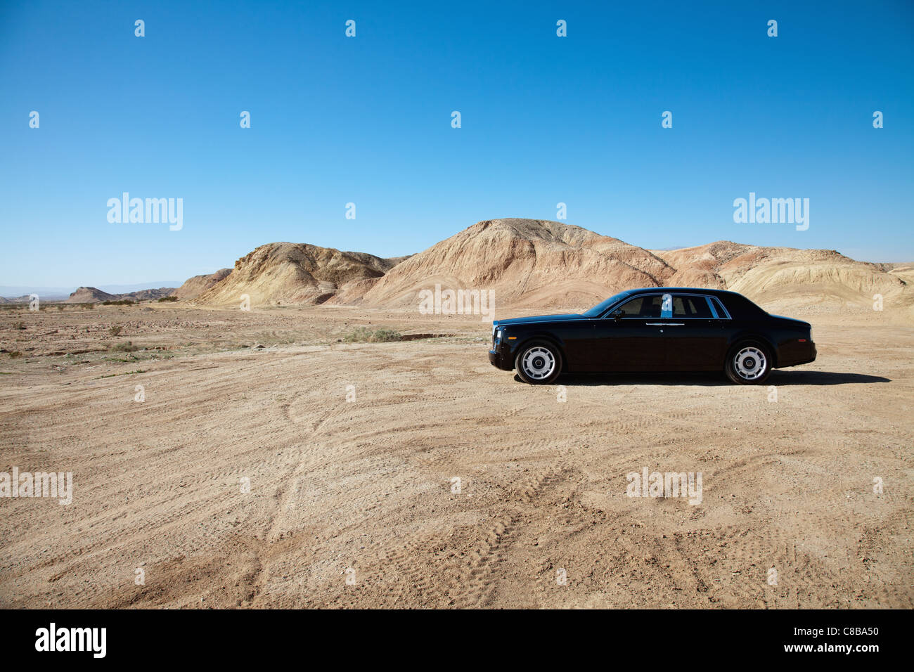 Luxury car parked on unpaved road near mountains Stock Photo