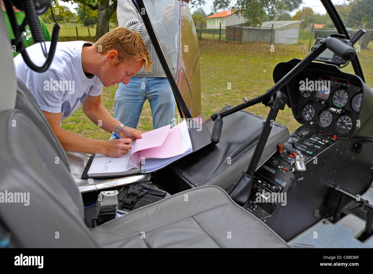 Co-pilot filling in flight log of a Robinson R22 Beta11 Helicopter Stock Photo