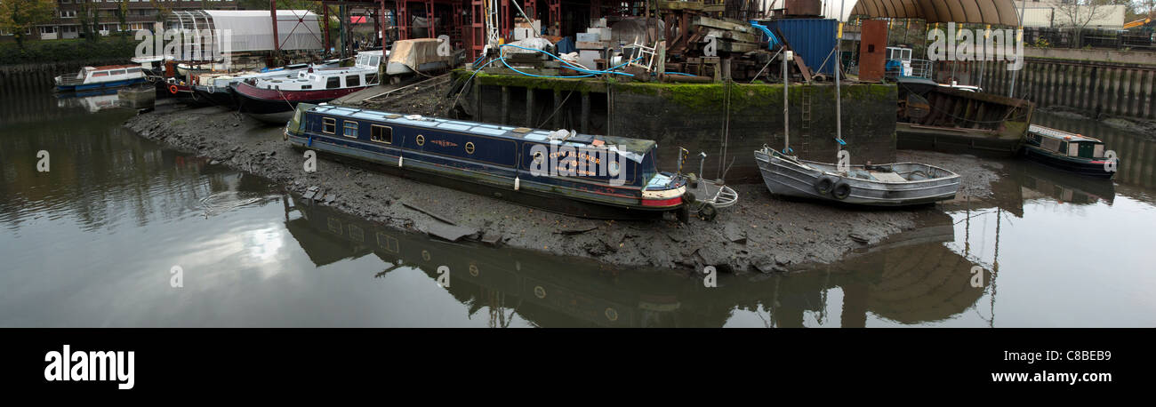 Narrowboat and barges at boatyard awaiting repair, River Thames at Brentford, London, UK Stock Photo