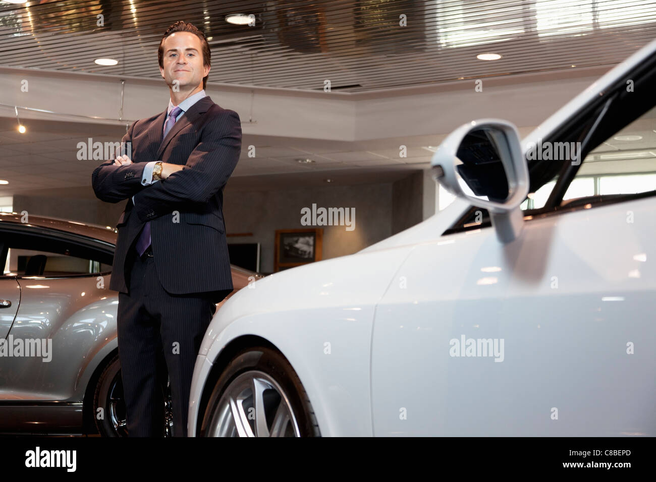 Confident car salesperson standing with arms crossed Stock Photo