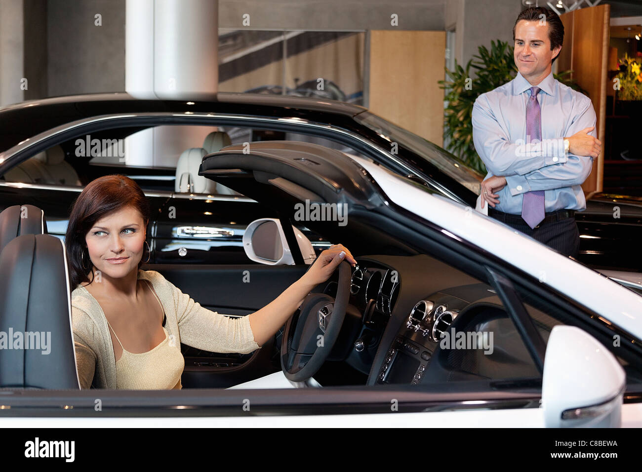 Woman having a test drive while salesperson standing besides car Stock Photo