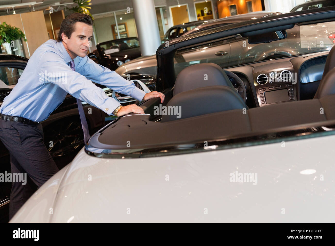 Car salesperson leaning on car Stock Photo