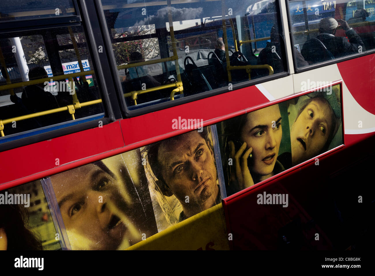 Faces of actors from the film Contagion adorn the upper deck of a red London double-decker bus. Stock Photo