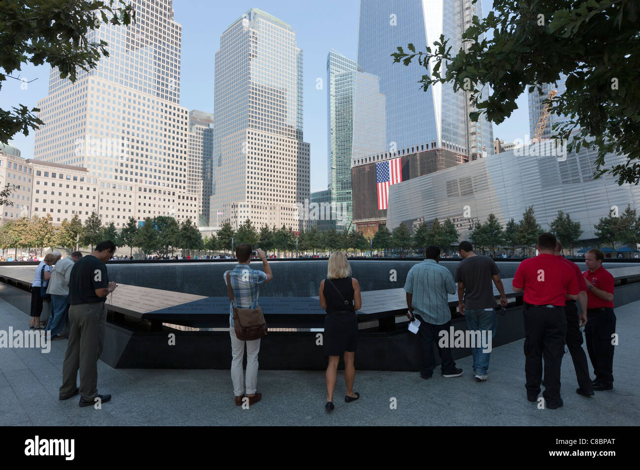 Visitors stand by the South Pool at the National September 11 Memorial in New York City. Stock Photo