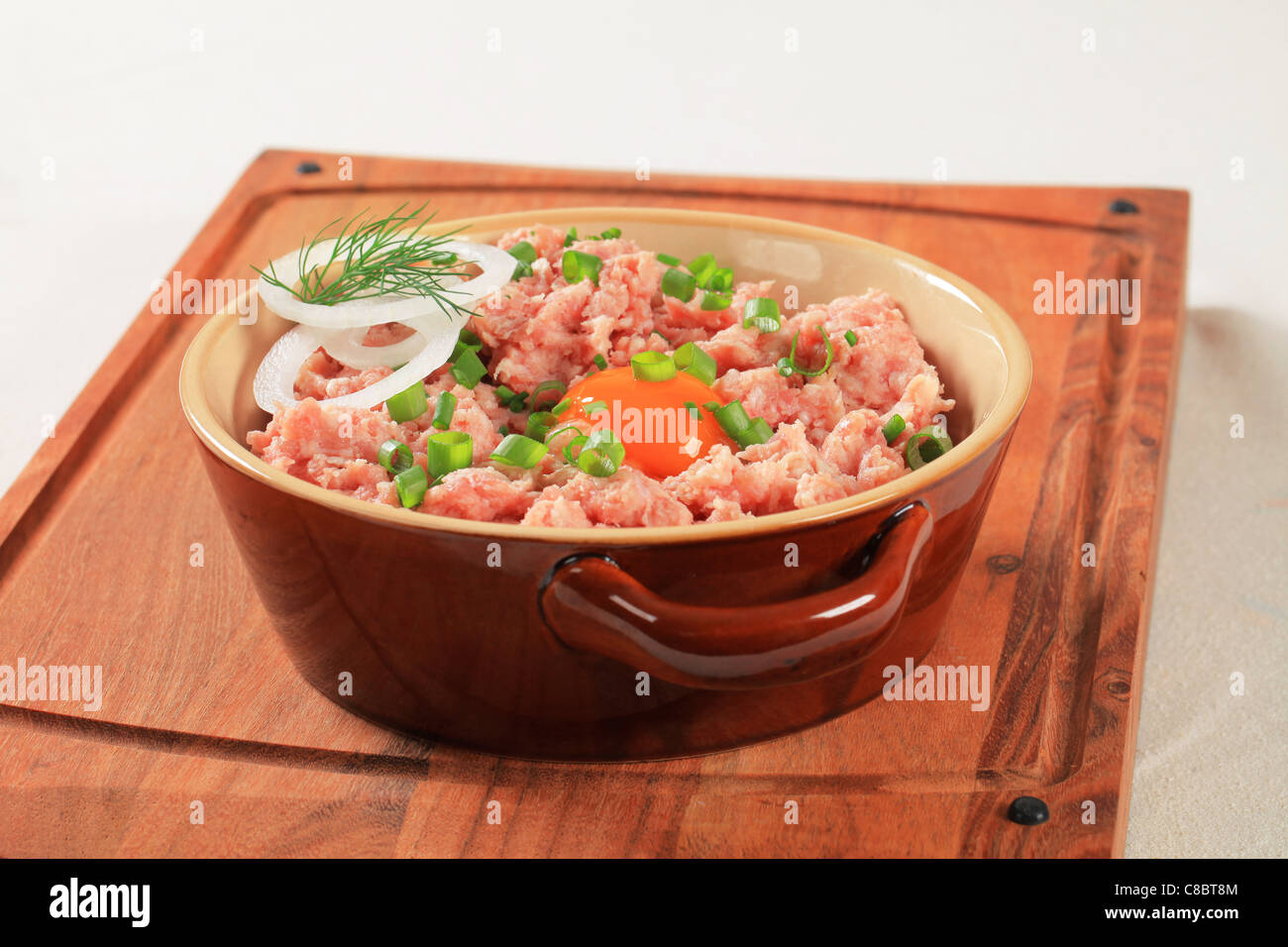 Ground meat and other ingredients in a ceramic pot Stock Photo