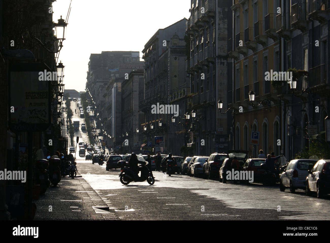 Steep street (Via Antonino di Sangiuliano) built with black Etna's magma in Catania on Sicily during late afternoon Stock Photo