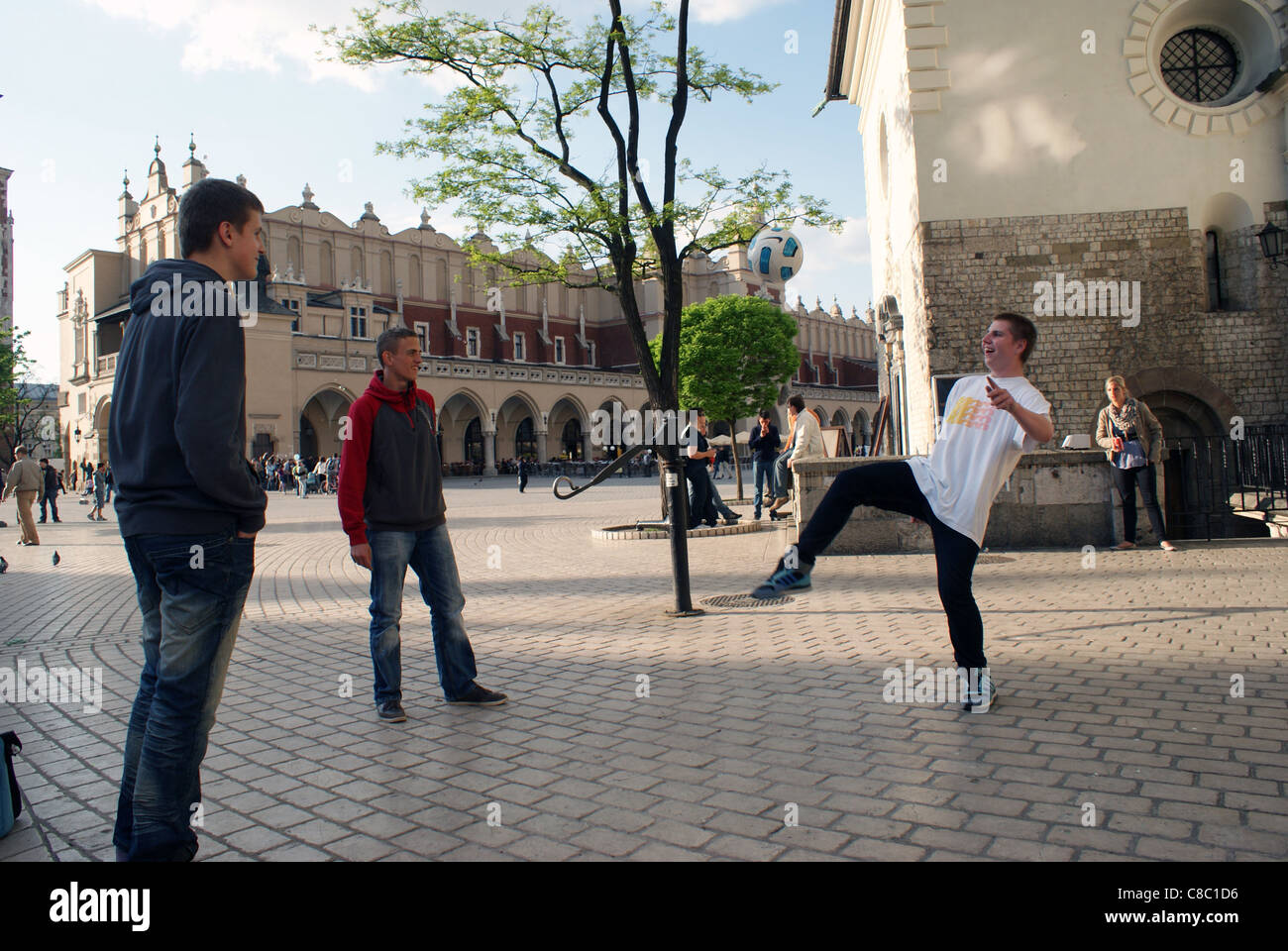 Young boys are playing football on Main Square in Cracow, near to Church of St. Adalbert. Stock Photo