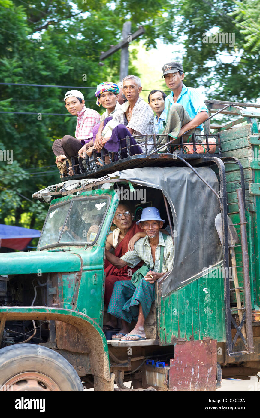 A truck overcrowded with passengers drives down road in Bagan, Myanmar Stock Photo