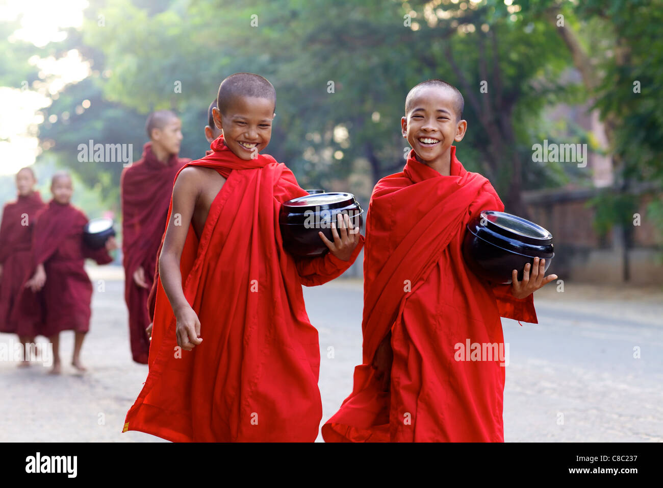 Unidentified young novice monks carrying bowls on morning alms walk Stock Photo