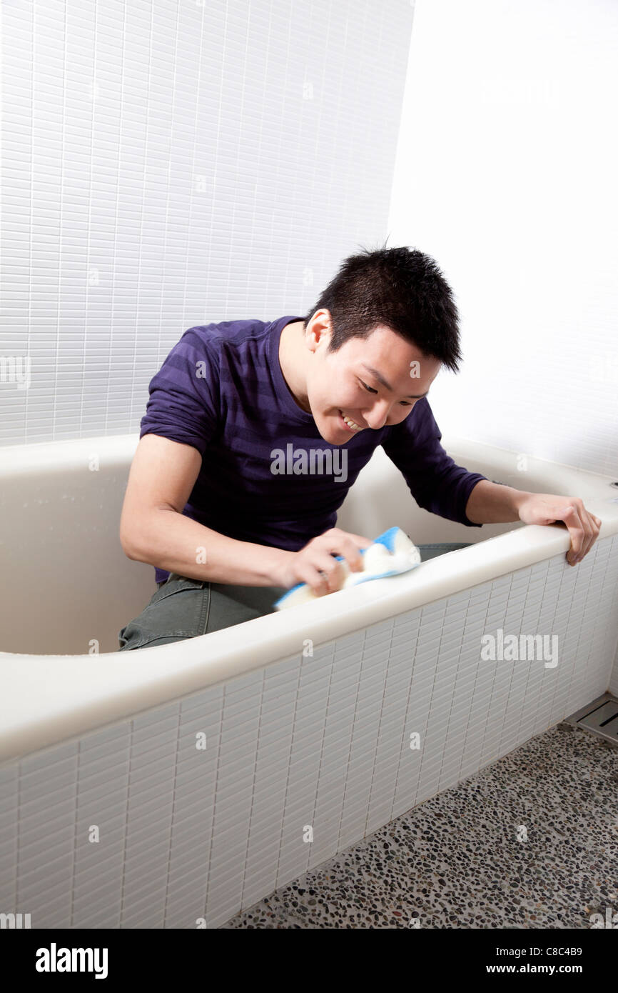 Young man scrubbing bathtub Stock Photo