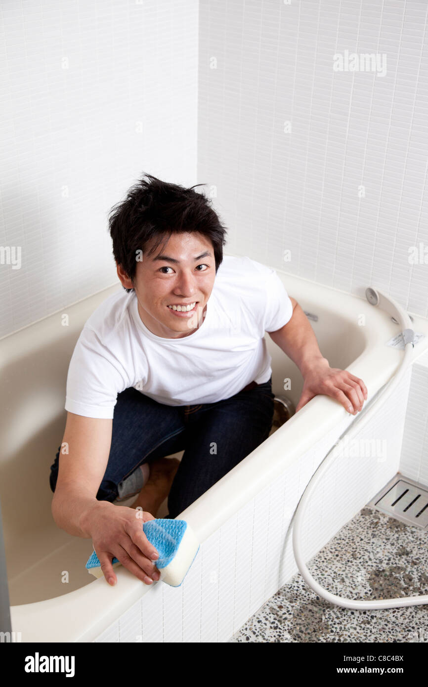 Mid adult man scrubbing bathtub Stock Photo